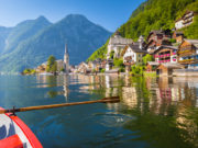 Scenic postcard view of famous Hallstatt lakeside village in the Austrian Alps with traditional wooden rowing boat in beautiful morning light on a sunny day in summer, Salzkammergut region, Austria