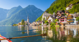 Scenic postcard view of famous Hallstatt lakeside village in the Austrian Alps with traditional wooden rowing boat in beautiful morning light on a sunny day in summer, Salzkammergut region, Austria