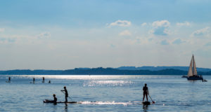 Silhouette of stand up paddle boarders paddling at Lake Chiemsee in Bavaria, Germany