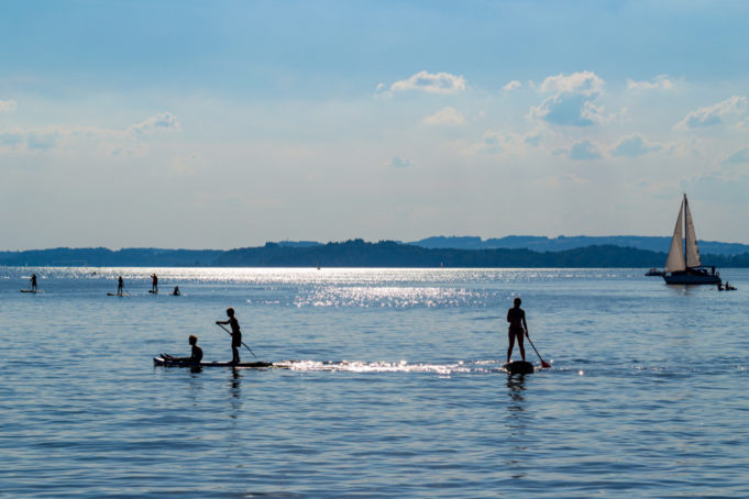 Silhouette of stand up paddle boarders paddling at Lake Chiemsee in Bavaria, Germany