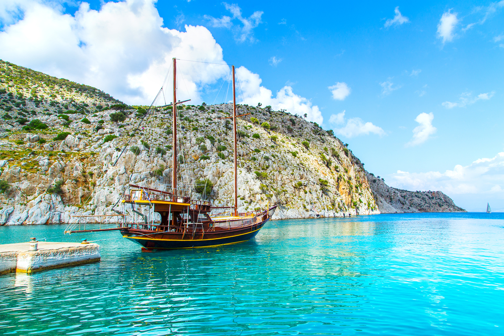 Wooden yacht standing in cosy port on Greek island with clear blue water, Greece