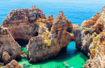 Ponta da Piedade - unique rock formation in the ocean - two boats with tourists visiting famous grottoes. Number one attraction in Lagos, Algrave, Portugal