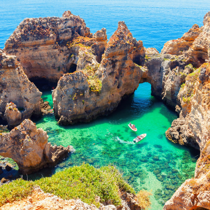 Ponta da Piedade - unique rock formation in the ocean - two boats with tourists visiting famous grottoes. Number one attraction in Lagos, Algrave, Portugal