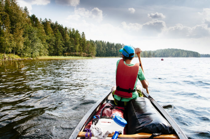 Teenager is paddling in a canoe in the Saimaa lake area / Saimaa, finland, europe