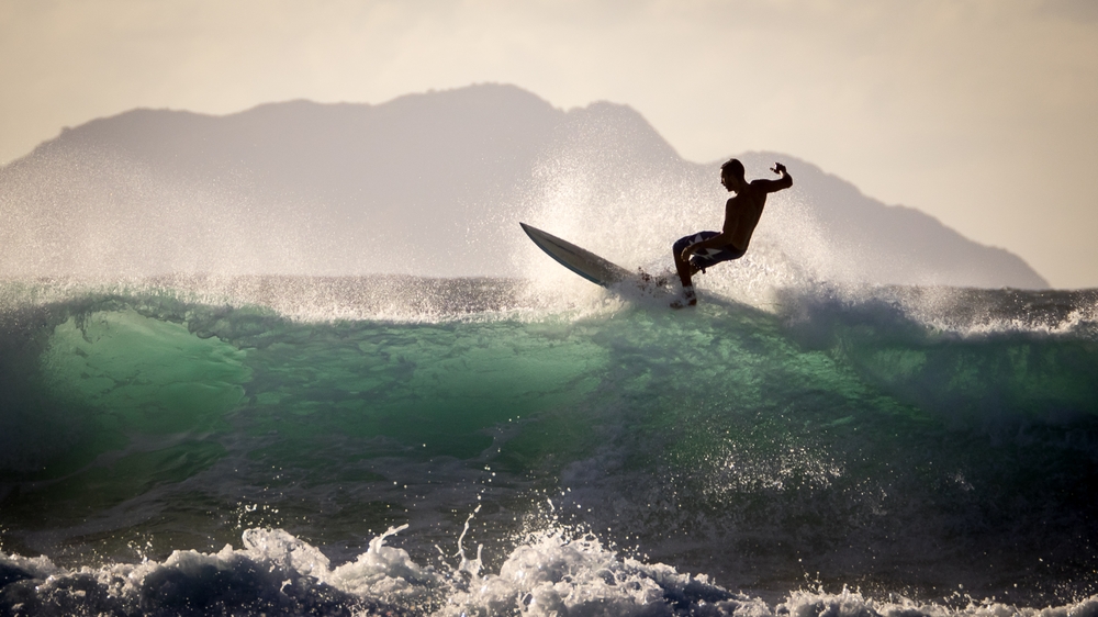 Aquadilla, Puerto Rico, USA - November 24 2014: Sportive person surfing at the coast of Puerto Rico during sunset.